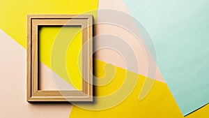 Empty classic wooden photo frame on pink, yellow and blue.