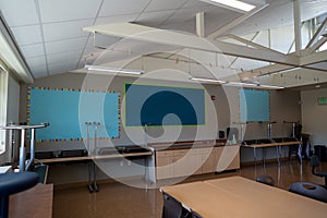 Empty classroom with blank decorations and tables and chairs stacked during summer