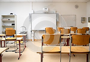 Empty classroom with an interactive whiteboard, desks and chairs