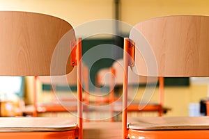 Empty classroom with school desks, chairs and blackboard.