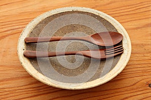 Empty clay dish with wooden cutlery on a dining table