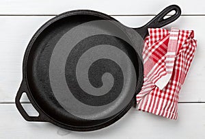 Empty, clean black cast iron pan or dutch oven top view from above on white table with towel