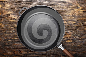 empty clean cast iron skillet on a wooden background.