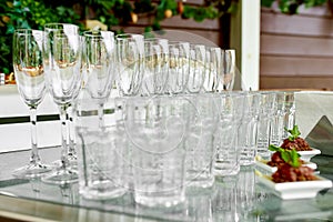 Empty, clean, crystal champagne glasses and crystal glasses for water stand on a serving table