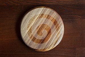An empty, clean cutting board with a beautiful texture on a dark wooden table