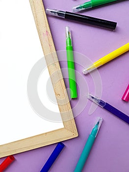 Empty clean white sheet for the buyer`s text on the purple background and school supplies, pencils. Back to school.