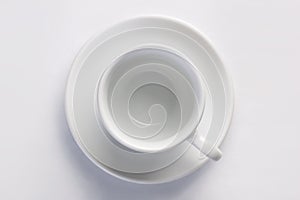 Empty clear coffee cup on saucer against white background, top view