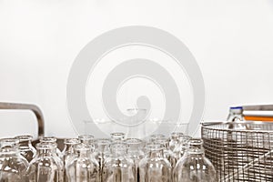 Empty clear glass medicine bottles stand on a cart. Medical manufacturing background