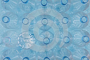 Empty clear plastic bottles without caps stacked on a blue background. Recycling and environment concept