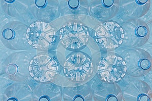 Empty clear plastic bottles without caps stacked on a blue background. Recycling and environment concept