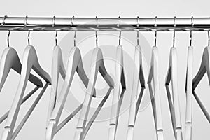 Empty clothes hangers on metal rail against light background