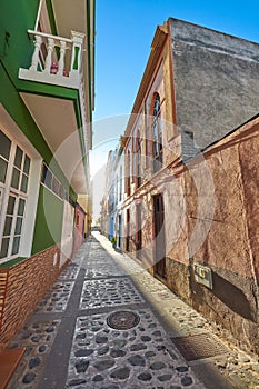 Empty cobbled street in a rural European tourist town. A quiet narrow alley way with colorful apartment buildings or