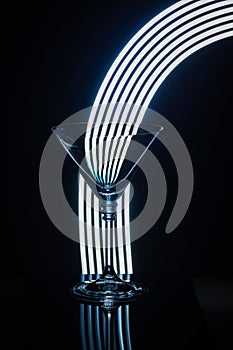 Empty martini glass on a black background with light painting