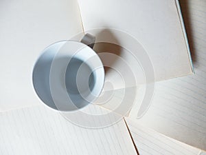 Empty coffee cup and blank paper sheets