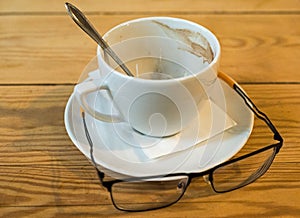 Empty coffee cup with grounds, saucer, binoculars and spoon