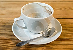 Empty coffee cup with grounds, saucer and spoon