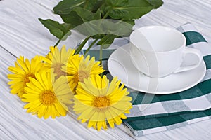 Empty coffee cup and saucer with yellow daisies