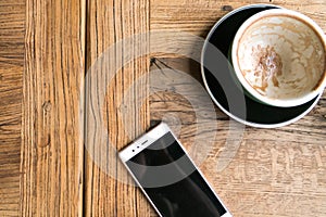 The empty coffee cup with the smart phone on the wooden table