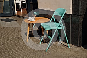 Empty coffee tables in a row, chairs on the sidewalk.