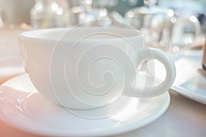 Empty coffee or tea cup on white table. White cup with hot drink on a morning table. Table set up to serve coffee or tea