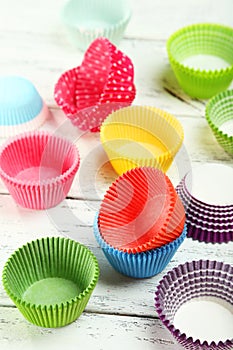 Empty colorful cupcake cases on wooden background