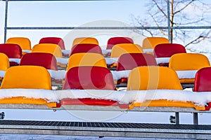 Empty Colorful Football Soccer Stadium Seats in the Winter Covered in Snow - Sunny Winter Day with Clear Blue Sky in the