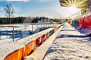 Empty Colorful Football & x28;Soccer& x29; Stadium Seats in the Winter Covered in Snow - Sunny Winter Day with Sun Flare