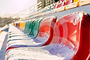 Empty Colorful Football (Soccer) Stadium Seats in the Winter Covered in Snow - Sunny Winter Day with Sun Flare