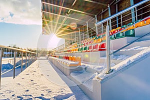 Empty Colorful Football (Soccer) Stadium Seats in the Winter Covered in Snow - Sunny Winter Day with Sun Flare