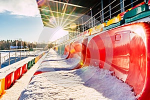 Empty Colorful Football & x28;Soccer& x29; Stadium Seats in the Winter Covered in Snow - Sunny Winter Day with Sun Flare