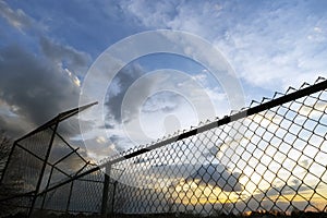 Empty community baseball diamond and fence in silhouette against