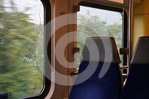 Empty commuter train on a rainy day, the windows are covered by raindrops.