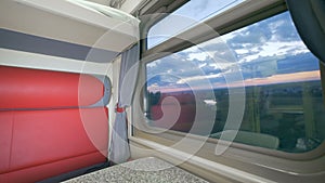 Empty compartment with a big window in a passenger train. Summer journey concept.