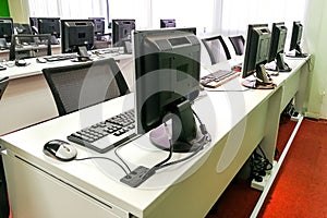 Empty computer classroom with monitors on top of table