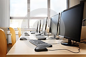 Empty computer room with monitors and keyboards in a row for pupils and students in a school computer lab