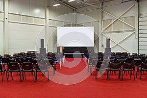 Empty conference hall with a screen and red carpet ready for a public seminar