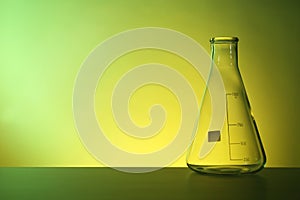 Empty conical flask on table against color background.