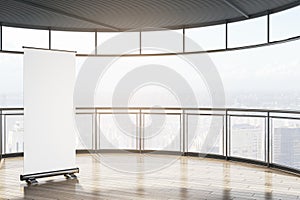 Empty contemporary spacious balcony with empty white roll-up mock up banner, glass railings and mock up place, bright city view.