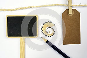 Empty copy space tag on a rope with a small blackboard, pencil, pencil shavings on white background