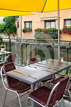 Empty cosy french street cafe or brasserie located on small river with served tables ready for visitors photo
