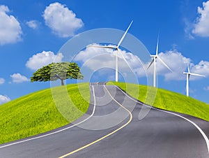 Empty country asphalt road with big tree and wind turbines on green field