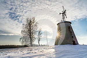 Empty Countryside Landscape in Sunny Winter Day with Snow Covering the Ground with Big Abandoned Windmill in Background