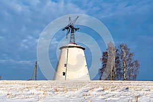 Empty Countryside Landscape in Sunny Winter Day with Snow Covering the Ground with Big Abandoned Windmill in Background