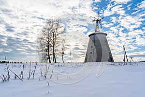 Empty Countryside Landscape in Sunny Winter Day with Snow Covering the Ground with Big Abandoned Windmill in Background