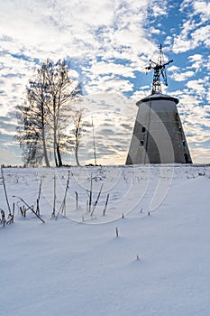 Empty Countryside Landscape in Sunny Winter Day with Snow Covering the Ground with Big Abandoned Windmill in Background