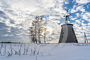 Empty Countryside Landscape in Sunny Winter Day with Snow Covering the Ground with Big Abandoned Windmill in Background