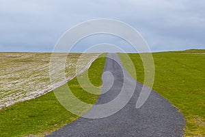 Empty countryside road running between green pastures photo