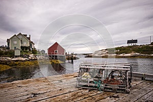 An empty crab cage in the foreground, houses in the background found in Peggy`s Cove in Halifax Nova Scotia