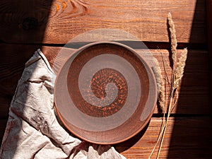 Empty craft handmade clay plate and pampas grass wooden background. Table place hand crafted dish Natural cottagecore