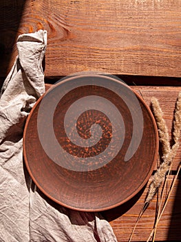 Empty craft handmade clay plate and pampas grass wooden background. Table place hand crafted dish Natural cottagecore